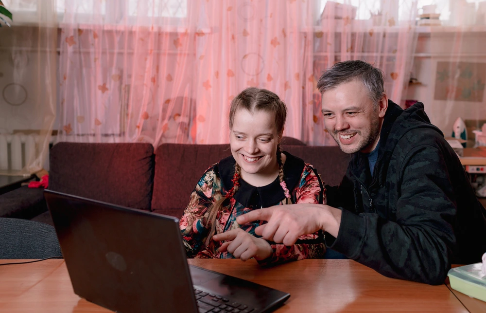 carer helping young disabled down syndrome girl